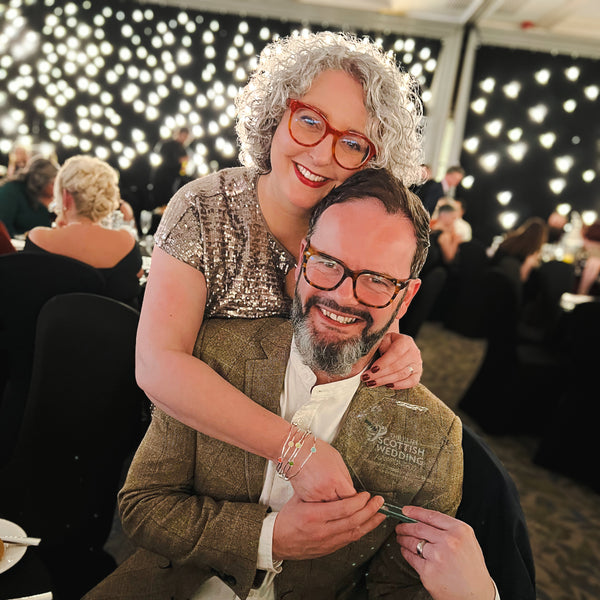 Picture of Suzanne and Richard at the Scottish Wedding awards, 2024, holding their Best Wedding stationery trophy.